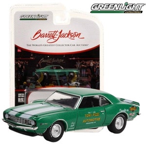 May include: A green die-cast model car with white racing stripes and the text "Tony Pizzi Automotive" and "Chevrolet on WEED". The car is a limited edition collectible from Greenlight Collectibles, featuring the Barrett-Jackson logo.