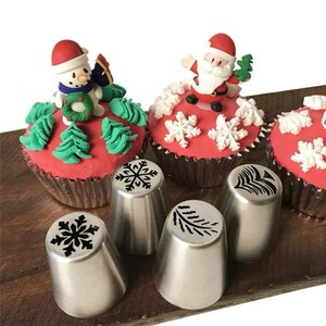 May include: Four stainless steel piping tips with snowflake and pine tree designs. The tips are used for decorating cupcakes and other baked goods.