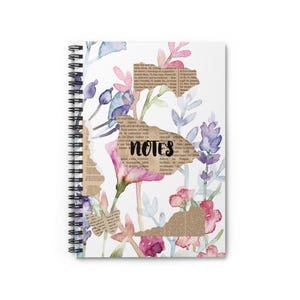 May include: Spiral-bound notebook with a floral design. The cover features watercolor-style flowers in pink, purple, and blue, with torn paper accents and the word "NOTES" in black. The notebook is white with a black spiral binding.