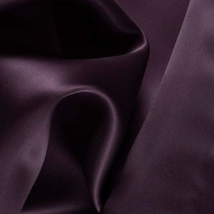 Peut inclure: Un gros plan sur un tissu lisse et soyeux d'une teinte violette profonde. Le tissu est drapé et plié, mettant en valeur sa texture luxueuse.