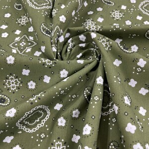 K&ouml;nnte beinhalten: Gr&uuml;ner Stoff mit einem wei&szlig;en Paisley-Muster. Der Stoff ist gefaltet und zeigt das sich wiederholende Muster.
