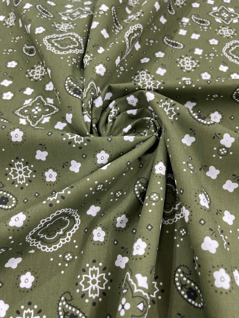 K&ouml;nnte beinhalten: Gr&uuml;ner Stoff mit einem wei&szlig;en Paisley-Muster. Der Stoff ist gefaltet und zeigt das sich wiederholende Muster.