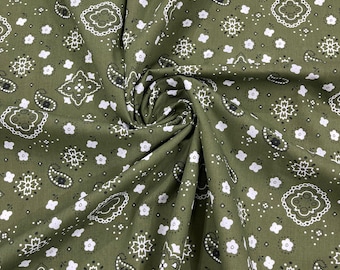 May include: Green fabric with a white and black paisley pattern. The fabric is folded and shows the pattern repeating.