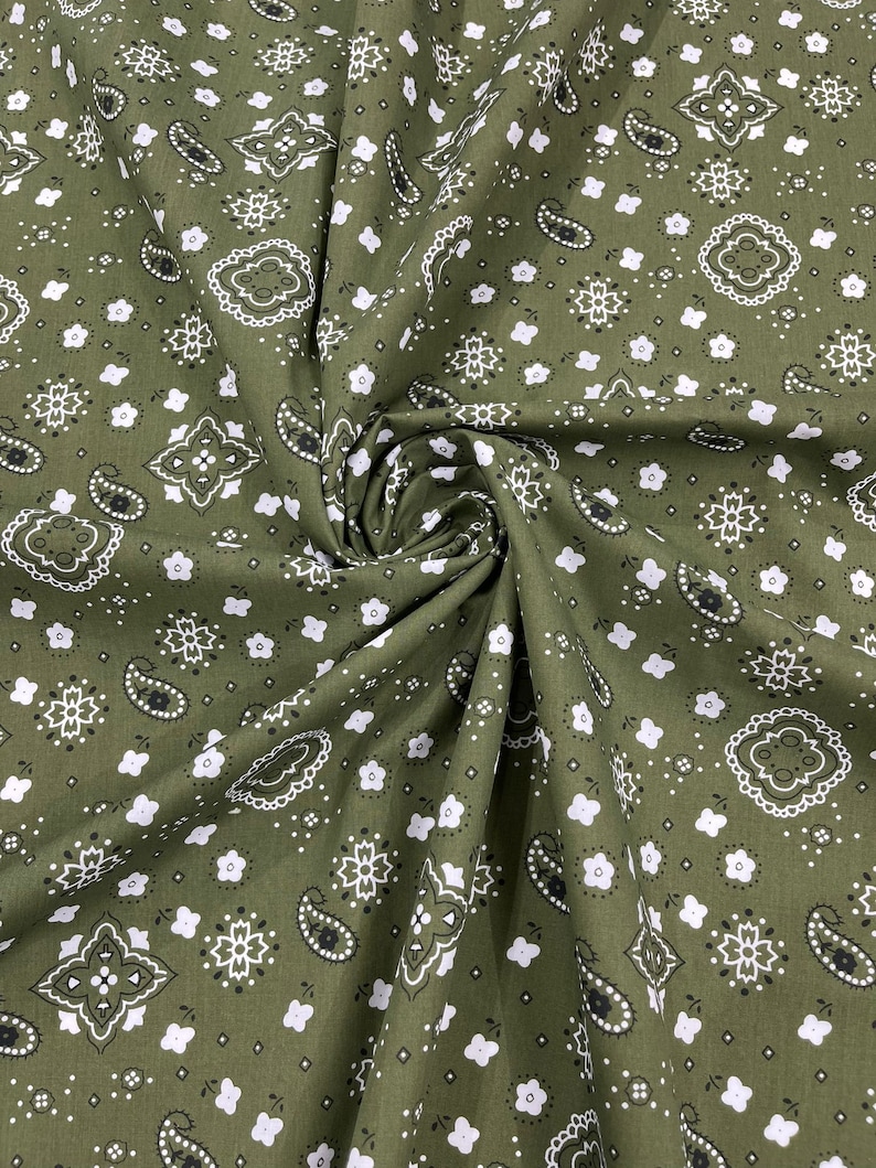K&ouml;nnte beinhalten: Gr&uuml;ner Stoff mit einem wei&szlig;en und schwarzen Paisley-Muster. Der Stoff ist gefaltet und zeigt das sich wiederholende Muster.