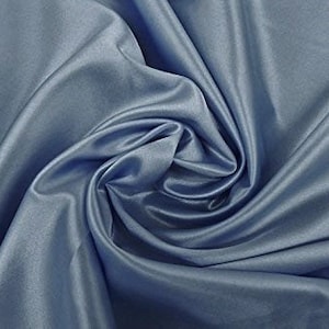 May include: A smooth, light blue fabric with a soft, silky texture. The fabric is draped and folded, creating a flowing, elegant look.