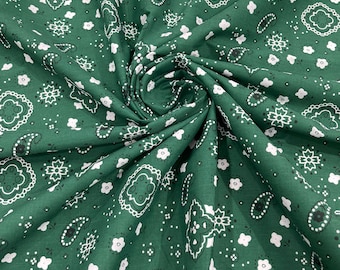 May include: Green fabric with a white and black paisley pattern. The fabric is folded and draped, showing the pattern.