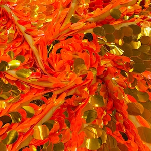 May include: Orange and gold sequin fabric with a circular pattern. The sequins are arranged in a swirling pattern, creating a dynamic and eye-catching design.