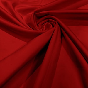 Peut inclure: Gros plan sur un tissu rouge lisse avec des plis et des rides doux. Le tissu est d'un rouge profond et riche et a une sensation luxueuse.