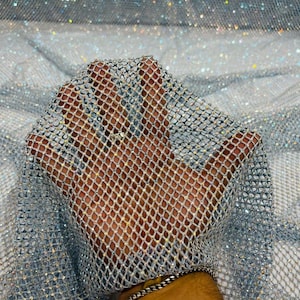 May include: Silver mesh fabric with iridescent sequins. The fabric is stretchy and has a loose weave.