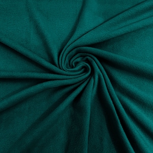 May include: A close-up of a teal green fabric with a soft, fuzzy texture. The fabric is folded and draped in a spiral pattern, creating a sense of depth and dimension.