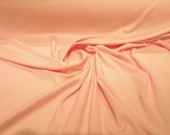 May include: Peach coloured fabric with a soft, smooth texture. The fabric is draped and folded, creating a flowing, elegant look.