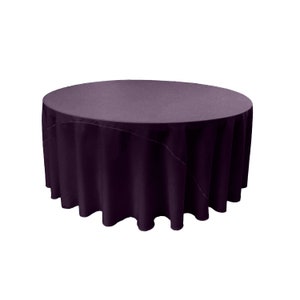 May include: A round, purple tablecloth with a smooth, even surface. The tablecloth is draped over a table and has a slight ruffle around the edge.
