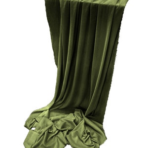 May include: A green fabric backdrop draped over a surface. The fabric is smooth and has a slight sheen. The backdrop is perfect for product photography or as a decorative element.
