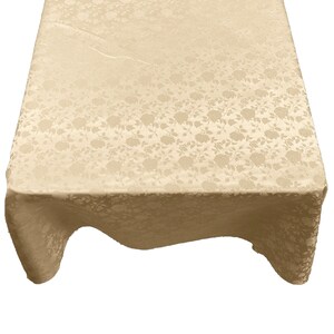 May include: A beige tablecloth with a floral pattern. The tablecloth is made of a soft, textured fabric.