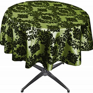 以下が含まれることがあります： 黒いダマスク模様のついた丸い緑色のテーブルクロス。テーブルクロスは銀色の脚のテーブルにかけられています。