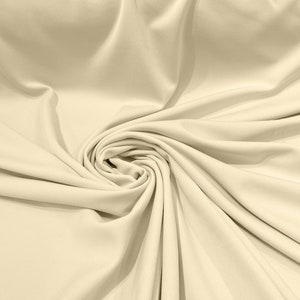 May include: A close-up of a smooth, cream-coloured fabric with soft folds and wrinkles. The fabric is draped and gathered in a swirling pattern, creating a luxurious and elegant texture.