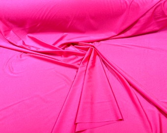 May include: A bright pink, stretchy fabric with a smooth, silky texture. The fabric is folded and draped, showcasing its flexibility and drape.