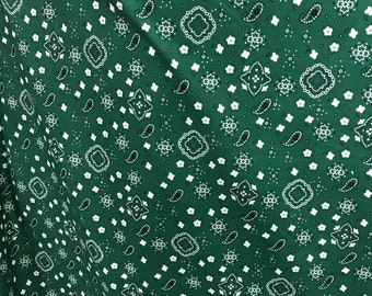 May include: Green fabric with a white paisley pattern. The fabric is folded in half, showing the pattern on both sides.