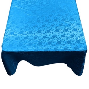 May include: A bright blue tablecloth with a floral pattern. The tablecloth is made of a satin-like material and has a slightly wrinkled appearance.
