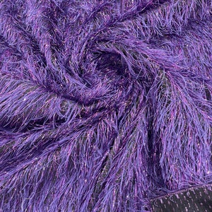 May include: Purple iridescent fringe fabric with a metallic sheen. The fabric is soft and fluffy, and it would be perfect for making a dress, skirt, or top.