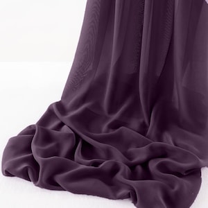 May include: A deep purple sheer fabric draped over a white surface. The fabric is soft and flowing, with a subtle sheen.