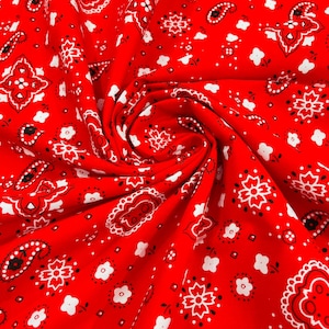 K&ouml;nnte beinhalten: Roter Stoff mit einem wei&szlig;en Paisley-Muster. Der Stoff ist gefaltet und verdreht, wodurch die Textur des Materials sichtbar wird.