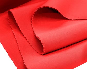 May include: Red fabric with a smooth texture. The fabric is folded in thirds and the edges are slightly frayed.