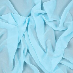 Pode incluir: Um tecido transparente de cor azul claro com uma textura suave e fluida. O tecido está drapeado e dobrado, criando uma aparência delicada e arejada.