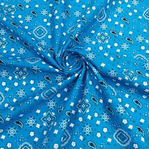 Pode incluir: Um close-up de um tecido azul com um padrão paisley branco. O tecido está dobrado e tem um toque macio e texturizado.