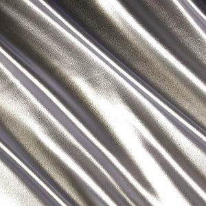 May include: Silver metallic fabric with a smooth, shiny surface and a subtle texture. The fabric is folded and draped, creating soft, flowing lines.