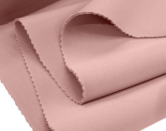 Puede incluir: Primer plano de un trozo de tela suave de color rosa claro doblado. La tela tiene una textura lisa y uniforme y un borde ligeramente texturizado.