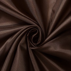 Könnte beinhalten: Nahaufnahme eines glatten, braunen Stoffes mit weicher, seidenartiger Textur. Der Stoff ist gefaltet und drapiert und erzeugt einen luxuriösen und eleganten Look.