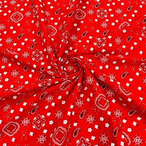 K&ouml;nnte beinhalten: Roter Stoff mit einem wei&szlig;en Paisley-Muster. Der Stoff ist spiralf&ouml;rmig gefaltet.