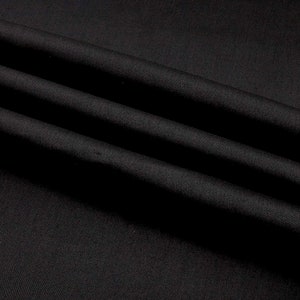 Könnte beinhalten: Schwarzer Stoff mit einer glatten, seidenartigen Textur. Der Stoff ist so gefaltet, dass er weiche, fließende Linien erzeugt.