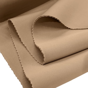 Puede incluir: Primer plano de un trozo de tela marrón doblado. La tela tiene una textura lisa y una superficie ligeramente texturizada.