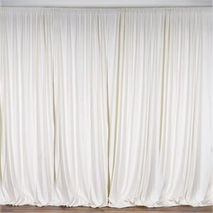 May include: A white backdrop made of fabric with a smooth texture. The backdrop is hung from a ceiling and has a slight drape.