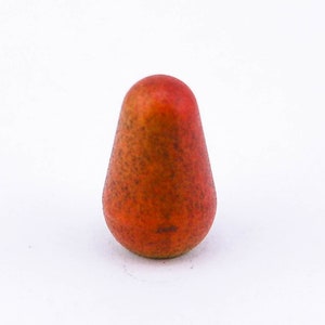 May include: A small, red, pear-shaped object with a textured surface.