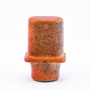 May include: A small, square, terracotta-colored ceramic pot with a rough, textured surface. The pot has a slightly flared base and a flat top.
