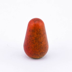 May include: A small, pear-shaped ceramic ornament with a mottled orange and brown glaze.