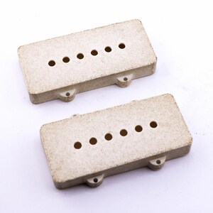 May include: Two beige plastic guitar pickup covers with six holes each.