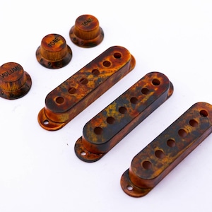 Könnte beinhalten: Drei braune und schwarze Gitarren-Tonabnehmerabdeckungen und drei Knöpfe mit den Aufschriften "Volume", "Tone" und "Tone".