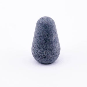 May include: A dark gray, pear-shaped, textured stone object.