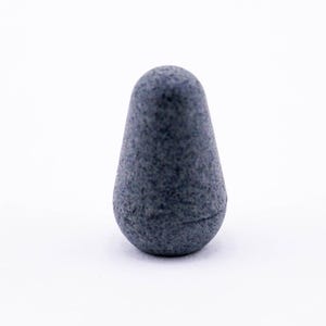 May include: A dark grey, pear-shaped, ceramic bottle stopper.