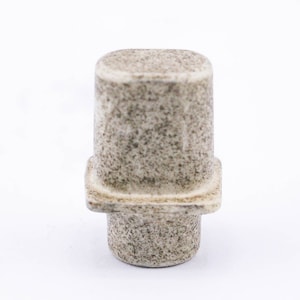 May include: A small, square, ceramic knob with a speckled, light brown and gray finish. The knob has a raised, square base and a cylindrical stem.