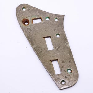 Op de afbeelding: Een zilverkleurige metalen gitaar pickguard met drie rechthoekige uitsparingen en verschillende kleine gaten rond de randen.