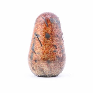 May include: A teardrop-shaped, ceramic bottle stopper. The stopper has a speckled, mottled appearance with shades of orange, brown, and gray. Dark gray streaks and spots add to the unique, textured design. The stopper is designed to fit into a bottle.
