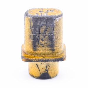 May include: A yellow ceramic electrical component with black markings. The component has a square base and a cylindrical top.
