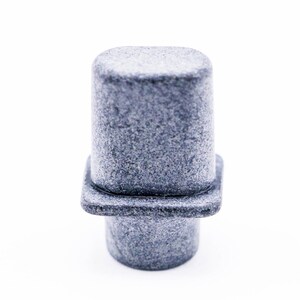 May include: A gray plastic knob with a square base and a rounded top. The knob has a textured surface.