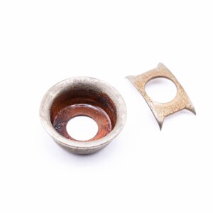 May include: A silver metal washer with a rusty interior and a matching silver metal ring.