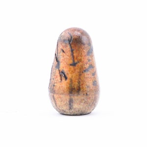 May include: A small, brown, ceramic, egg-shaped object with black and orange markings.